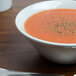 A Tuxton TuxTrendz bright white china bowl filled with soup with spices on top.