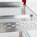 A stainless steel metal shelf with red handles and silver trim.