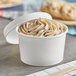 A Choice white paper food cup filled with ice cream on a counter.