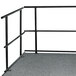A black metal National Public Seating guardrail on a grey carpet.