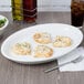 A Tuxton white oval china platter with food on it next to a bowl of salad on a table.