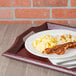 A mahogany plastic room service tray with a plate of food on it.