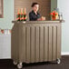 A woman standing behind a Cambro portable bar with drinks.