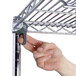 A hand attaching a metal shelf to a Metro wire shelving unit.