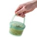 A hand holding a jade green GET Reusable Eco-Takeout Soup container.