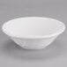 A Tuxton San Marino AlumaTux white China grapefruit bowl with a small rim on a gray surface.