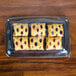 A Sabert clear plastic catering tray with a high dome lid covering pastries on a wood table.