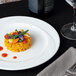 A Tuxton AlumaTux Pearl White China plate with rice and vegetables on a table.