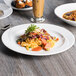 A white Tuxton AlumaTux plate of food on a table.
