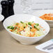 A Tuxton AlumaTux Pearl White slant bowl filled with salad with croutons and carrots.