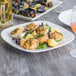 A Tuxton AlumaTux square china plate with mussels and a lemon wedge.