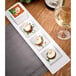 A Tuxton AlumaTux rectangular white china platter with food on a table.