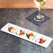 A Tuxton AlumaTux rectangular white china tray with 4 compartments on a table with a plate of food.