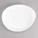 A Tuxton AlumaTux Pearl White China ellipse plate on a gray surface.