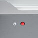 A close up of a red button on a grey surface.