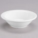 A Tuxton Modena AlumaTux pearl white fruit bowl on a gray surface.