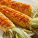 Two ears of corn on a plate with Regal ground cayenne pepper and salt.