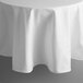 A white Intedge round tablecloth with hemmed edges on a round table.