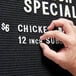 A person using Aarco Helvetica letter and number set to change a sign.