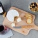 A Franmara cheese knife with a bamboo handle on a wooden cutting board with cheese and nuts.