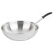 A Vollrath stainless steel stir fry pan with a black TriVent silicone handle.