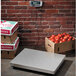 An Edlund digital receiving scale on a white surface with boxes of tomatoes on it.