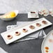 A 10 Strawberry Street white rectangular porcelain platter with cookies and a bowl of lemon wedges on it.