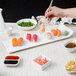 A person using chopsticks to eat sushi off a 10 Strawberry Street rectangular platter.