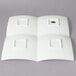 A white porcelain tray with four square compartments.