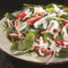 A plate of salad with tomatoes, spinach, and House Blend Ranch Sauce.