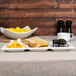 A white porcelain tray with 3 pockets holding a plate of toast, jam, and a bowl of fruit.