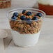 A Solo clear plastic cup filled with yogurt, granola, and blueberries.