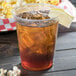 A Solo Ultra Clear plastic cup of iced tea with ice and a lemon wedge.