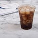 A Solo clear plastic squat cup filled with ice tea on a marble counter.