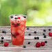 A Solo Ultra Clear PET plastic cup of red drink with ice and berries.