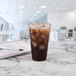 A Solo Ultra Clear plastic cup of iced coffee with ice cubes on a table.