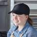 A woman wearing a black Headsweats 5-panel cap with a blue shirt.