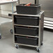 A Lakeside stainless steel utility cart with black containers on it.
