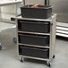A Lakeside stainless steel utility cart with black containers on top.