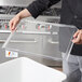 A person using a Cambro lid for an ingredient bin.