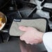 A person using a San Jamar BestGuard terry cloth pot holder to touch a surface.