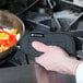 A person holding a black San Jamar Ultigrips hot pad over a pan of food.