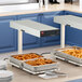A Hatco heated shelf with trays of food on a counter.
