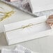 A person holding a large white candy box with gold ribbon.