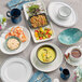 A white china creamer with a black rim on a table with blue and white dishes and food.