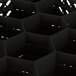 A black plastic Vollrath Traex glass rack with 12 hexagon-shaped compartments.