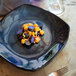 A close-up of a Tuxton Artisan Night Sky china plate of food with a fork and knife on the table.
