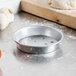 An American Metalcraft silver aluminum pizza pan on a counter.