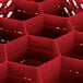 A red plastic Vollrath Traex glass rack with 12 compartments and hexagon shapes.