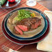 A Tuxton Artisan Red Rock china plate with steak and salad on it.